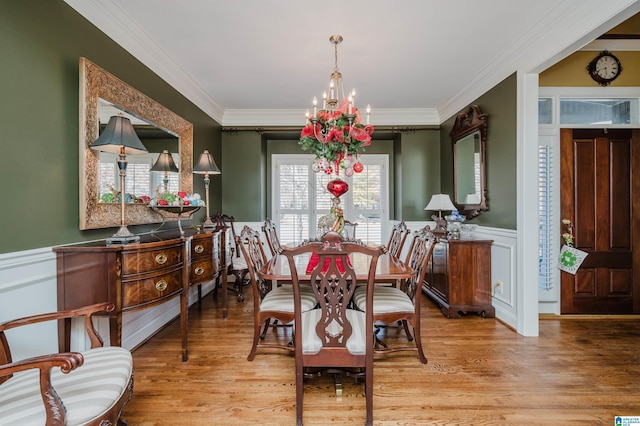 dining room with a wealth of natural light, ornamental molding, a notable chandelier, and light wood-type flooring