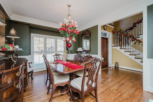 dining space with crown molding, light hardwood / wood-style flooring, and a chandelier