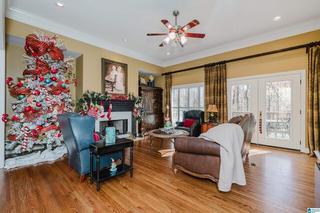 living room with light wood-type flooring, ceiling fan, and ornamental molding