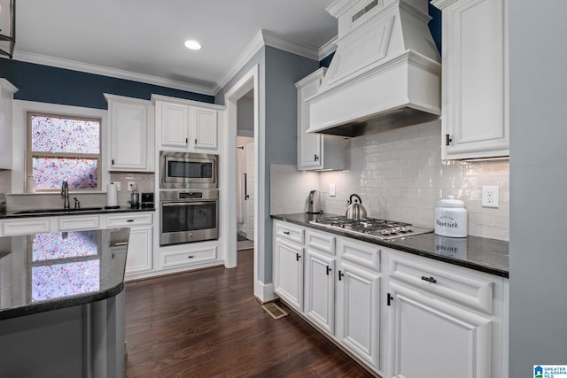 kitchen with custom exhaust hood, dark wood-type flooring, crown molding, appliances with stainless steel finishes, and white cabinetry