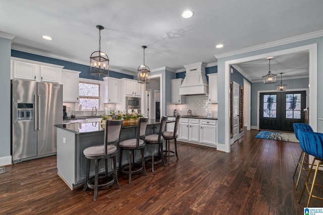 kitchen featuring french doors, custom range hood, stainless steel appliances, dark wood-type flooring, and a kitchen island