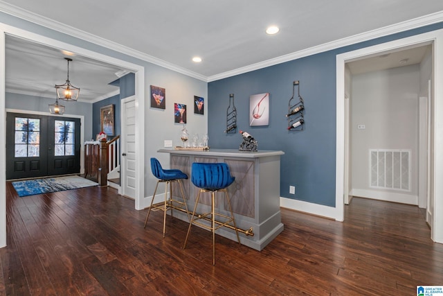 bar featuring pendant lighting, ornamental molding, dark wood-type flooring, and french doors