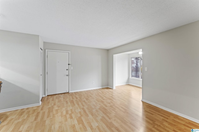 spare room featuring a textured ceiling and light wood-type flooring