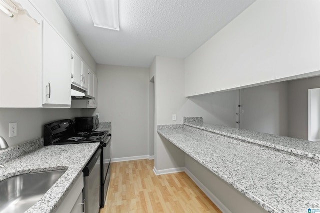 kitchen with light stone countertops, white cabinetry, light hardwood / wood-style floors, and appliances with stainless steel finishes