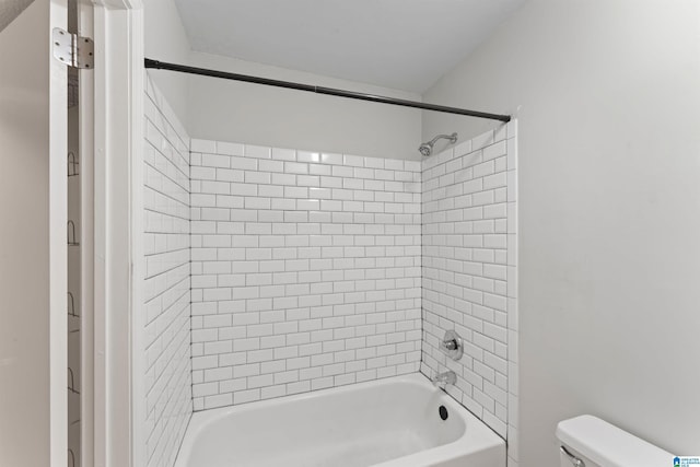 bathroom with tiled shower / bath combo and toilet