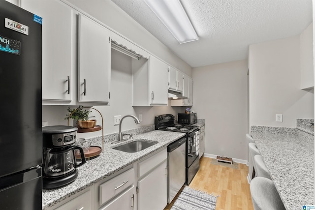 kitchen with sink, white cabinets, black appliances, light stone countertops, and light wood-type flooring