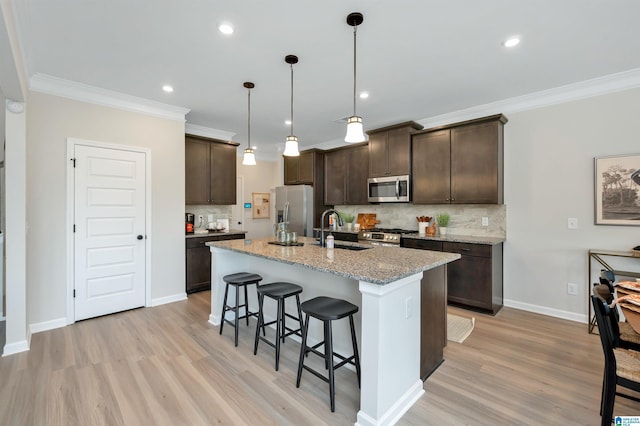 kitchen featuring light stone counters, stainless steel appliances, sink, a center island with sink, and light hardwood / wood-style floors