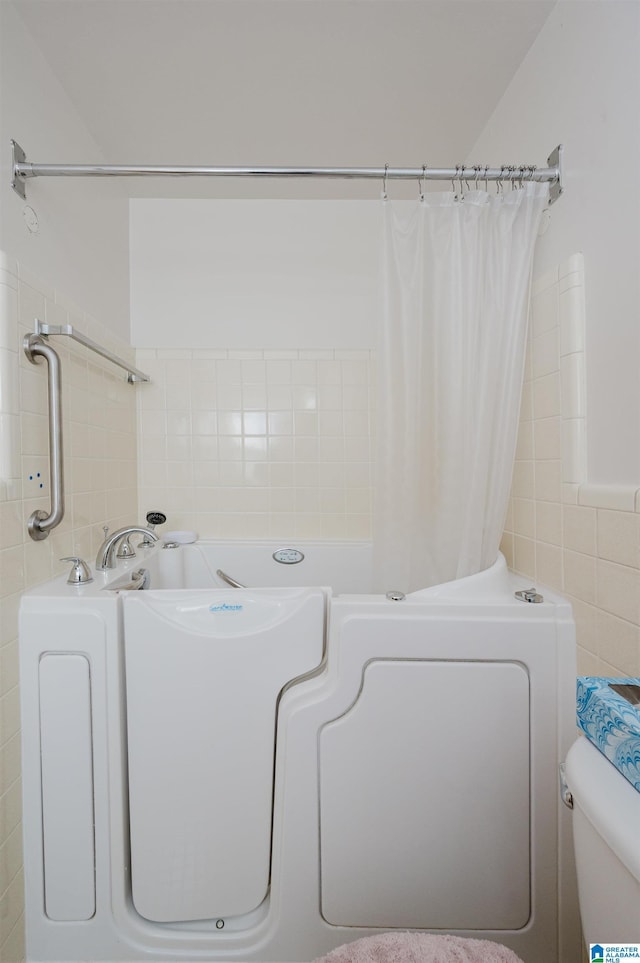 bathroom with toilet and tile walls