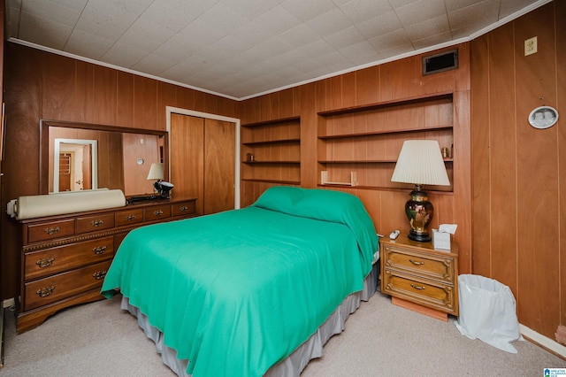 carpeted bedroom with ornamental molding, wooden walls, and a closet