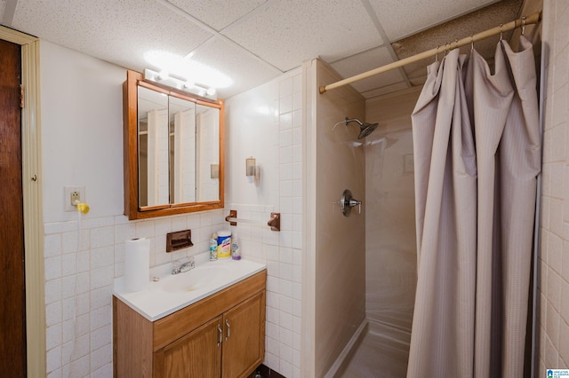 bathroom with a paneled ceiling, vanity, curtained shower, and tile walls