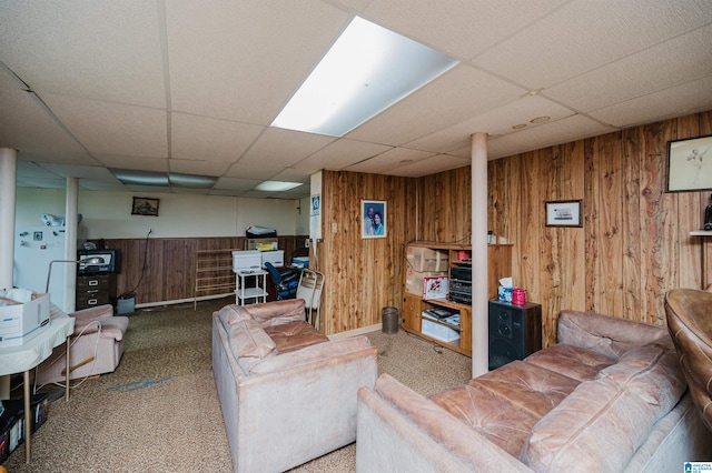 carpeted living room with a paneled ceiling and wood walls