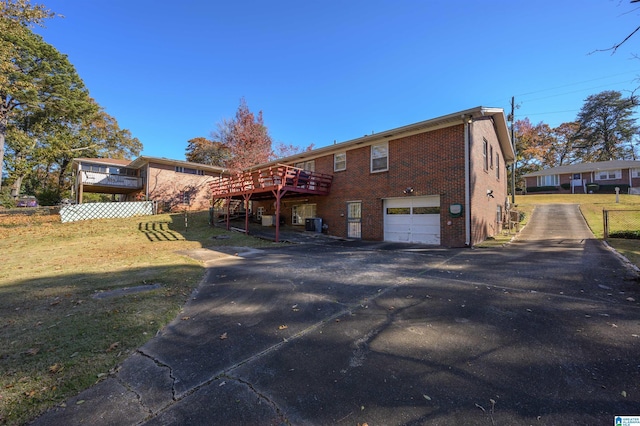 back of property with a garage, a deck, and a lawn