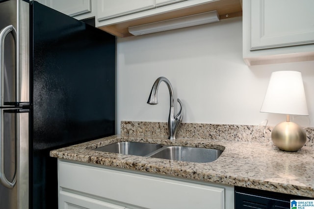 kitchen featuring white cabinets, stainless steel fridge, and sink