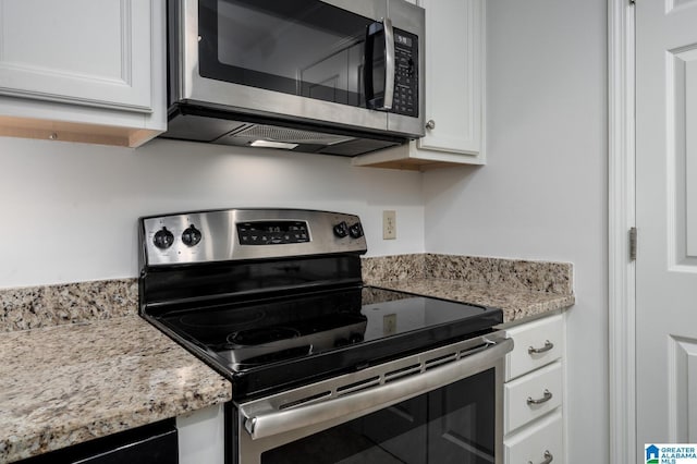 kitchen with light stone countertops, white cabinetry, and stainless steel appliances