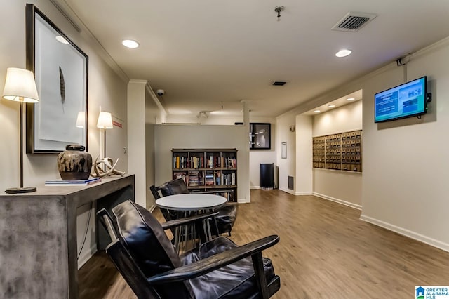 living area with crown molding and wood-type flooring