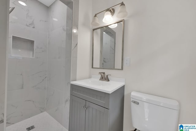 bathroom with vanity, toilet, and a tile shower