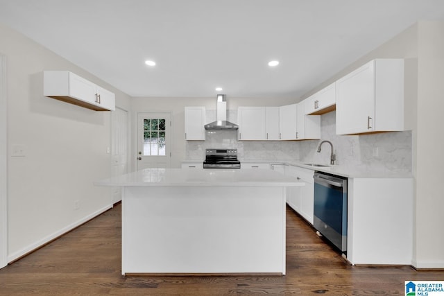 kitchen featuring white cabinets, a center island, stainless steel appliances, and wall chimney range hood