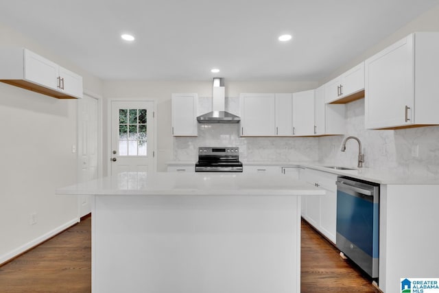 kitchen featuring white cabinets, a kitchen island, wall chimney range hood, and appliances with stainless steel finishes