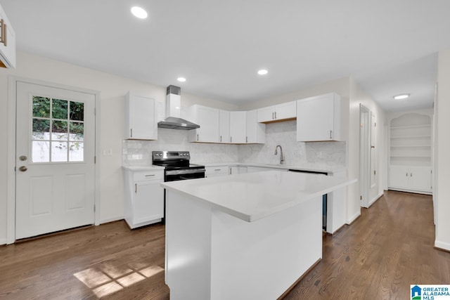 kitchen featuring dark hardwood / wood-style flooring, wall chimney exhaust hood, white cabinetry, a kitchen island, and stainless steel range with electric cooktop