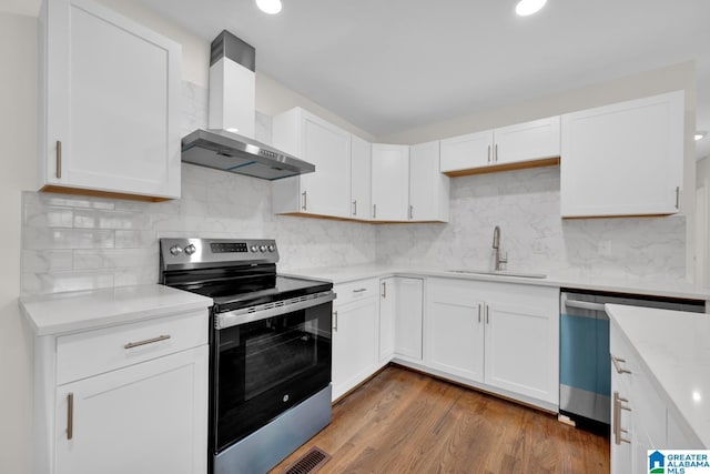 kitchen featuring white cabinetry, sink, wall chimney range hood, dark hardwood / wood-style floors, and appliances with stainless steel finishes