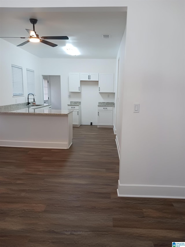 kitchen featuring dark wood-type flooring, white cabinets, sink, ceiling fan, and light stone countertops