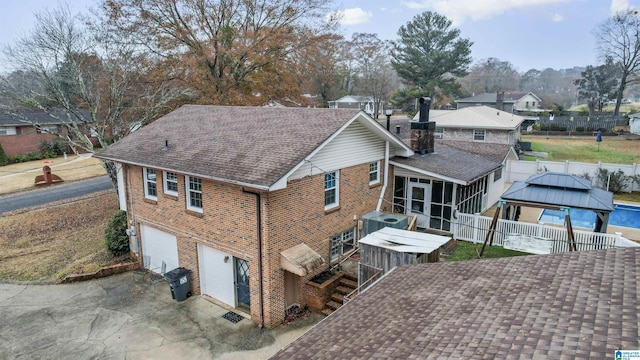 back of property with a gazebo, a garage, central AC unit, and a sunroom