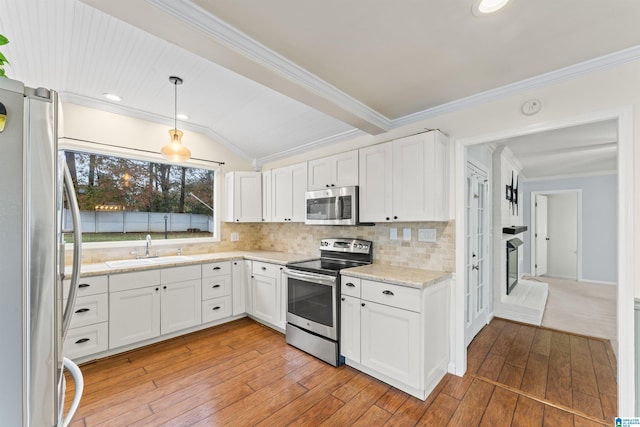 kitchen with stainless steel appliances, sink, decorative light fixtures, light hardwood / wood-style flooring, and white cabinetry