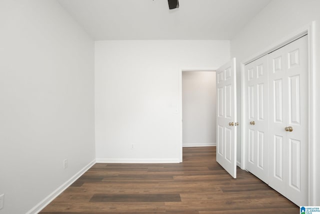 unfurnished bedroom featuring ceiling fan, a closet, and dark wood-type flooring