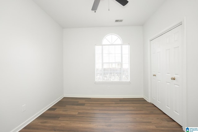 empty room with ceiling fan, dark wood-type flooring, and a healthy amount of sunlight