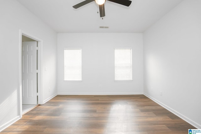 unfurnished room featuring ceiling fan, dark wood-type flooring, and a healthy amount of sunlight