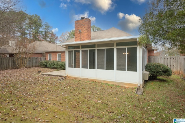 back of house featuring a sunroom and a lawn