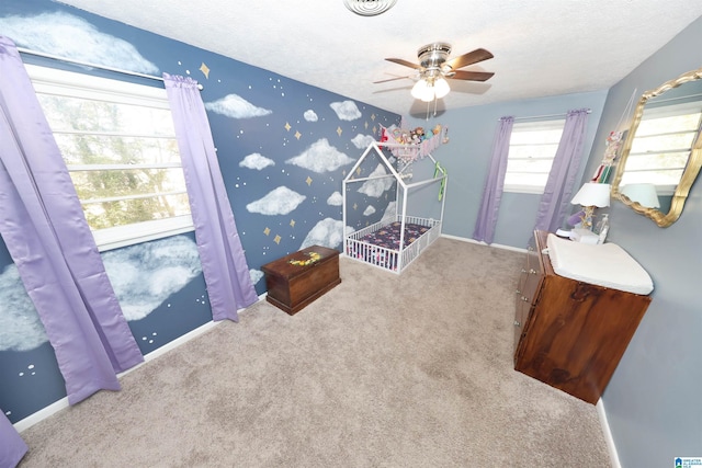 bedroom with a textured ceiling, light colored carpet, and ceiling fan