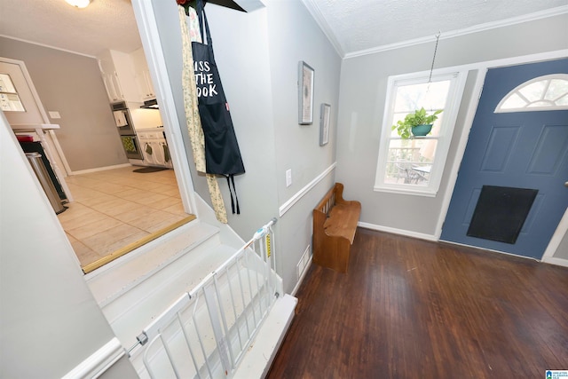 foyer with dark wood-type flooring, a textured ceiling, and ornamental molding