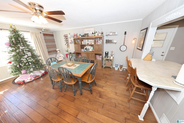 dining room with ceiling fan, crown molding, and hardwood / wood-style flooring