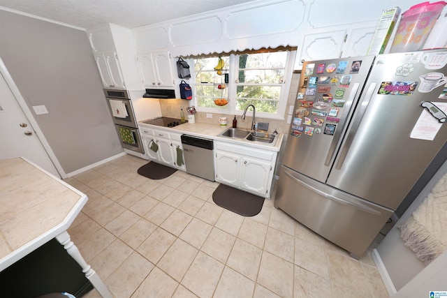 kitchen with a textured ceiling, stainless steel appliances, sink, light tile patterned floors, and white cabinetry