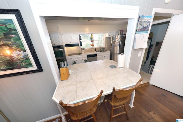 kitchen with appliances with stainless steel finishes, dark hardwood / wood-style flooring, sink, white cabinetry, and a breakfast bar area