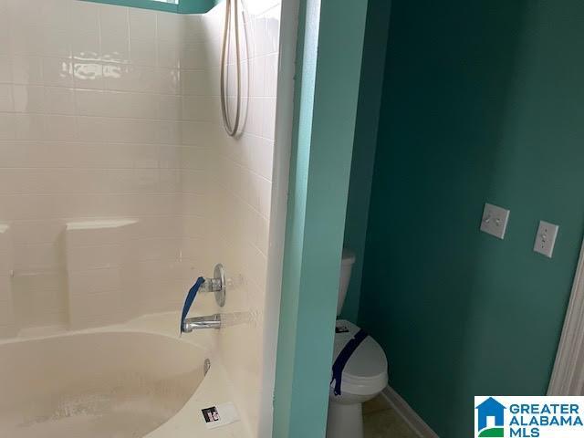 bathroom featuring toilet and tiled shower / bath