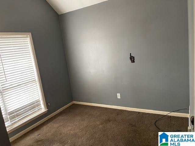 carpeted empty room featuring lofted ceiling