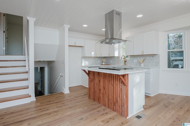 kitchen featuring white cabinets, light wood-type flooring, island range hood, and a kitchen island