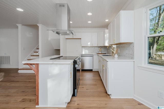 kitchen featuring ventilation hood, white cabinets, light wood-type flooring, appliances with stainless steel finishes, and a kitchen island