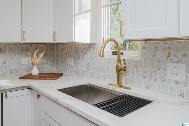 details with light stone counters, white cabinetry, tasteful backsplash, and sink