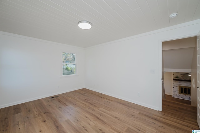 empty room featuring wood-type flooring and a brick fireplace