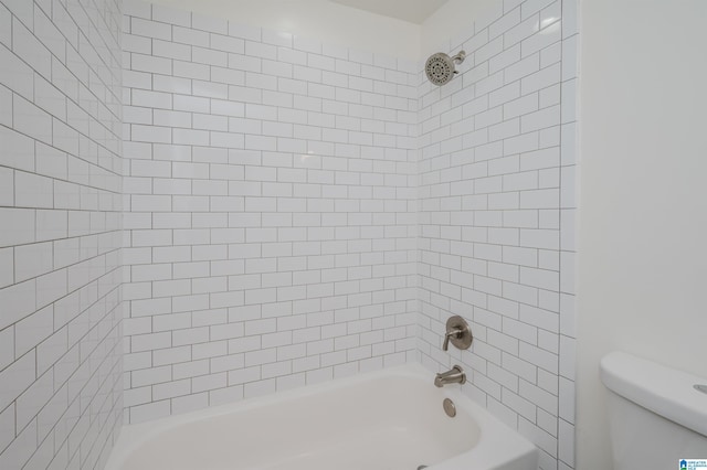 bathroom with tiled shower / bath combo and toilet