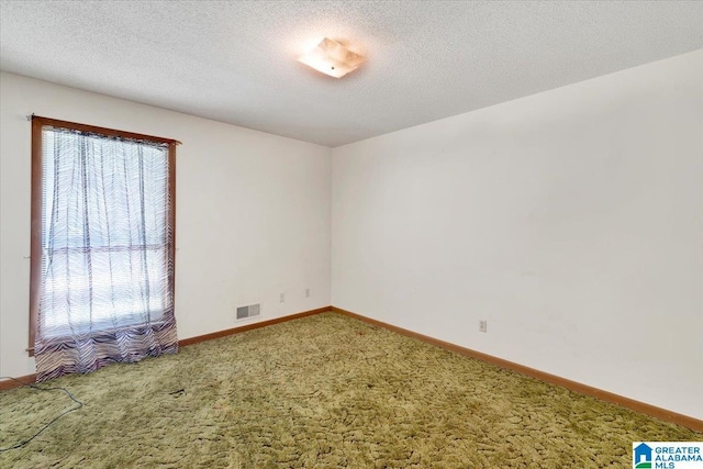 carpeted empty room featuring a textured ceiling