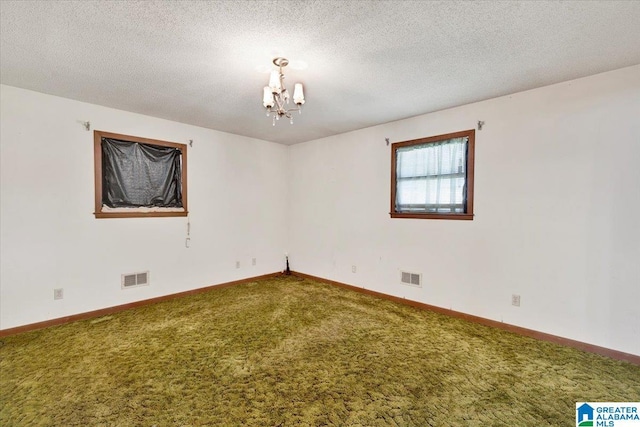 empty room with carpet floors, a textured ceiling, and an inviting chandelier