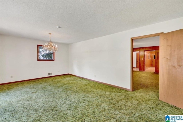 carpeted spare room with a chandelier and a textured ceiling