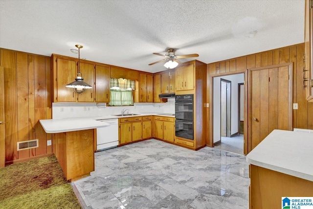 kitchen featuring sink, hanging light fixtures, kitchen peninsula, wood walls, and black appliances