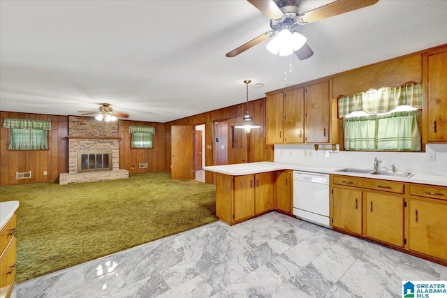 kitchen with kitchen peninsula, light colored carpet, pendant lighting, dishwasher, and wood walls