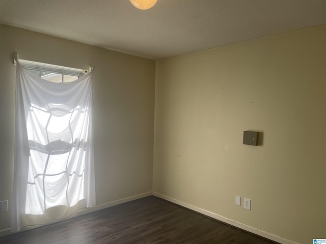 spare room featuring a textured ceiling and dark wood-type flooring