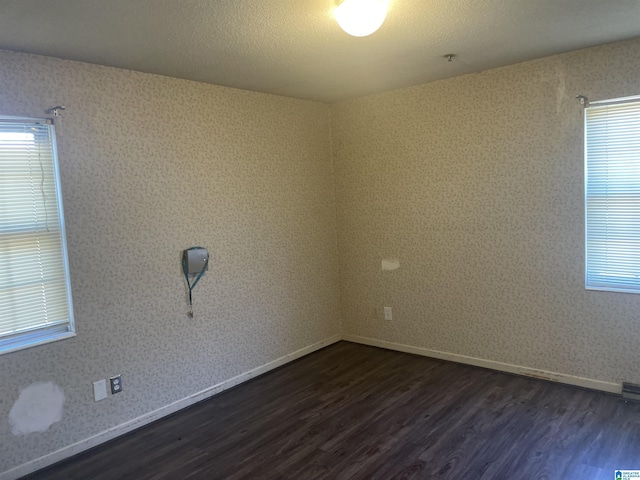 unfurnished room with a textured ceiling and dark hardwood / wood-style floors